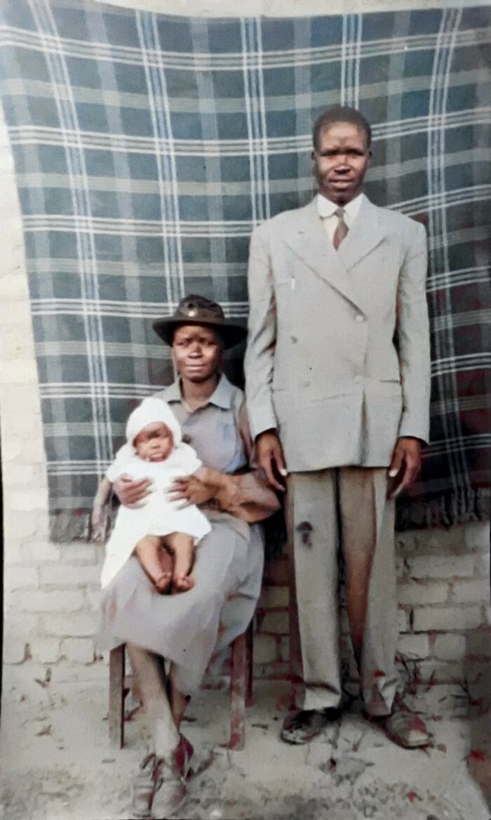 En bild på ett svart par som poserar för ett porträtt. Kvinnan håller i ett barn i sina knän.