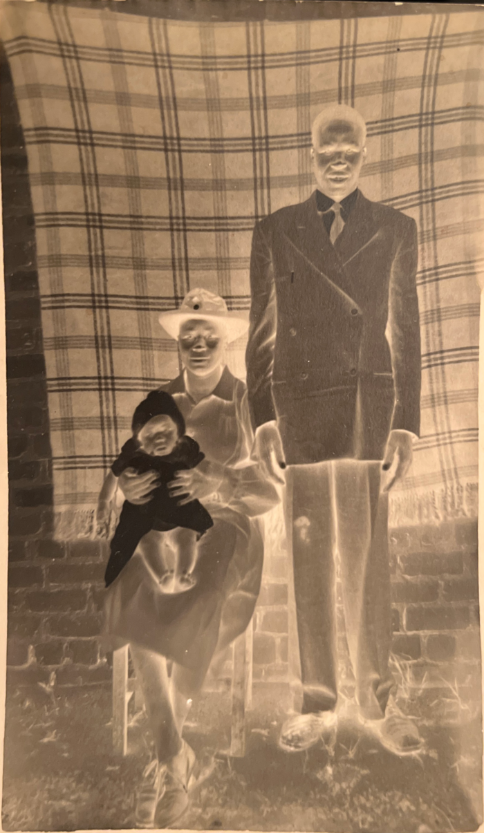 A negative of a picture of a couple taking a portrait. the woman holds a baby on her lap.